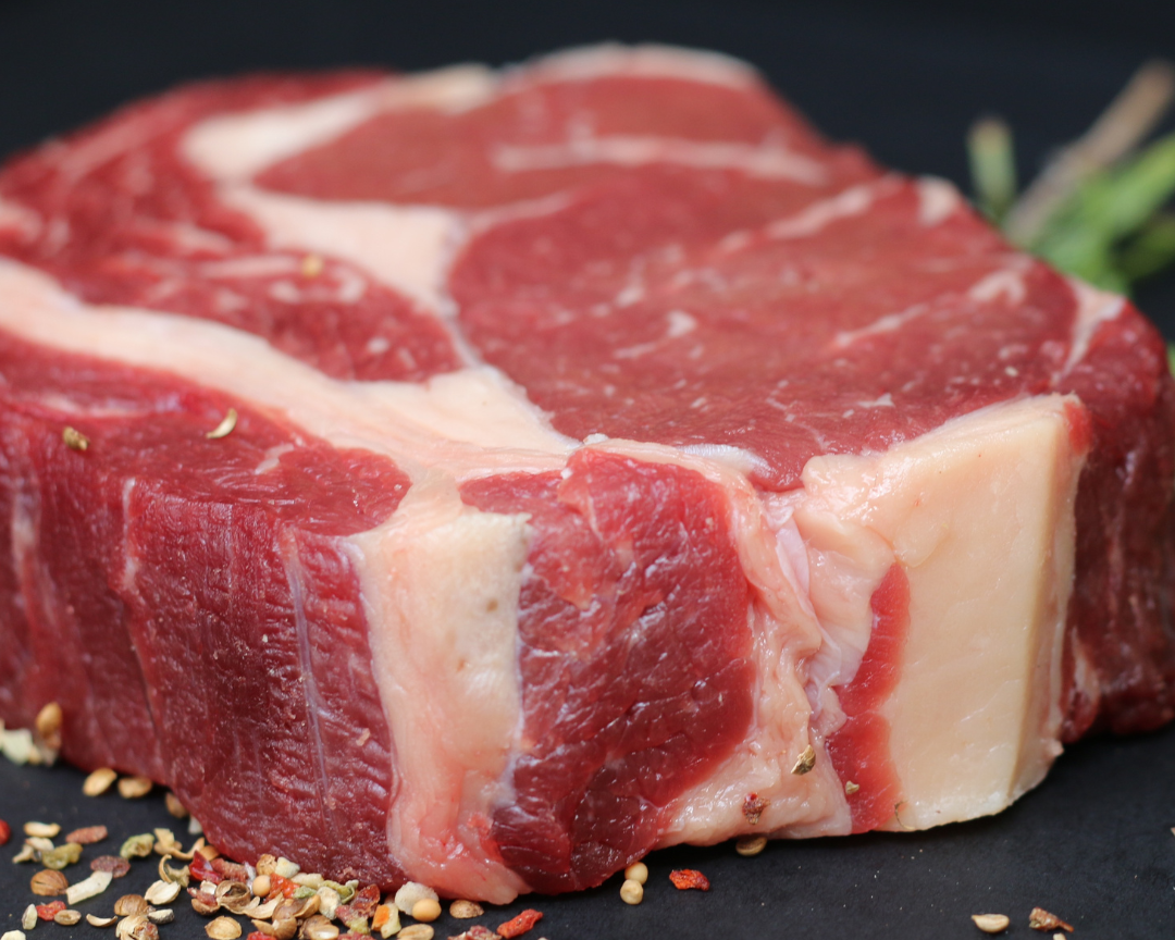Raw steak with spices on a dark surface