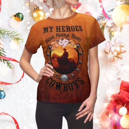 Person wearing a t-shirt with a cowboy graphic and text in front of a decorated Christmas tree.